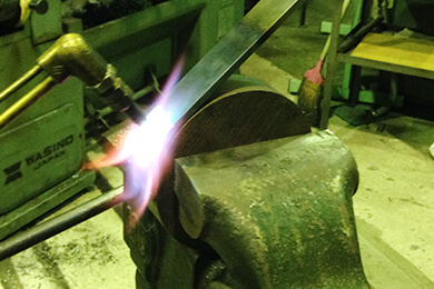 １．丸い鉄に鋼材を溶接機で点止め固定し、そのRにそって、ガス溶断の炎で熱して、炙りながら手曲げをしていきます。
